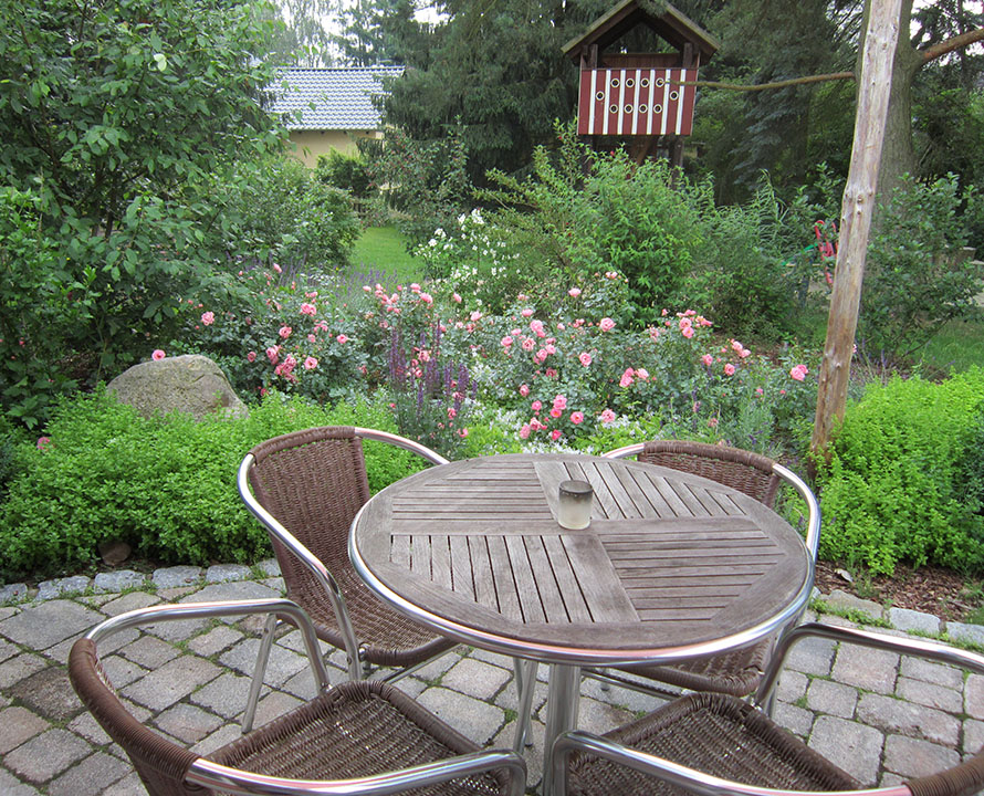 Terrasse mit Gartenmöbeln und Blick auf Rosen "the fairy" und grüne Büsche
